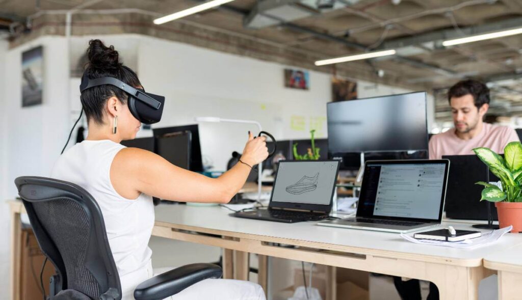 Mulher utiliza óculos de realidade virtual enquanto projeta em 3D num escritório moderno, simbolizando inovação em contexto de formação-ação.