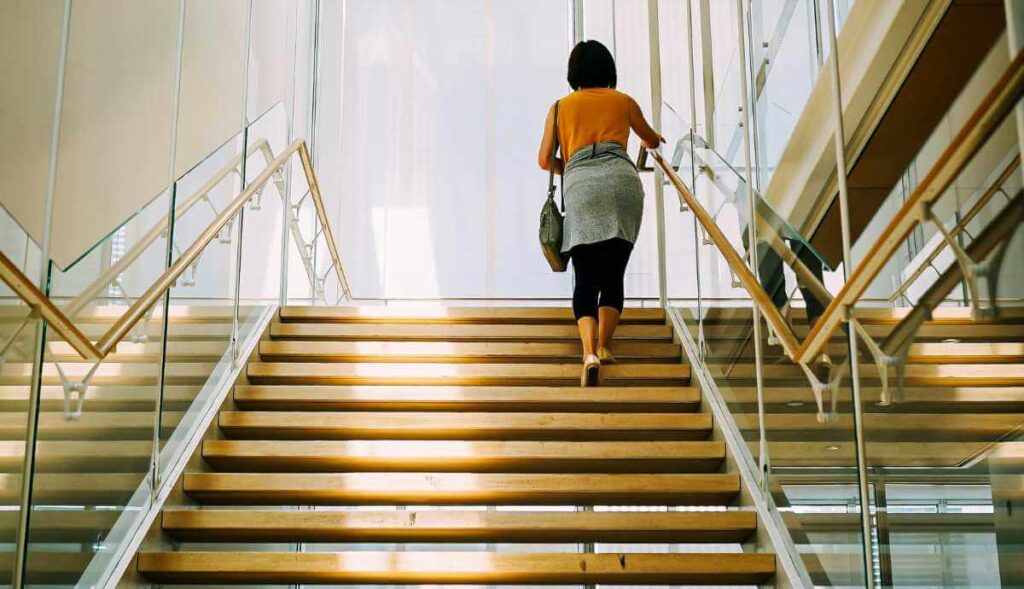 Mulher a subir escadas simbolizando o progresso de uma PME através da formação-ação.