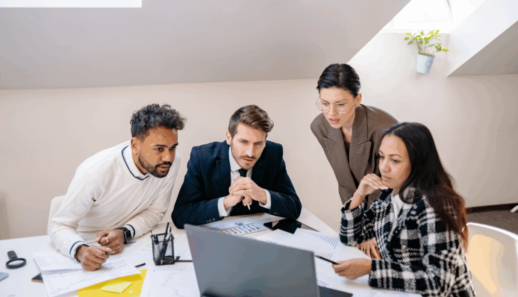 Equipa de RH em reunião a analisar documentos e computador, ilustrando parceria com fornecedor externo para gerir formação contínua obrigatória